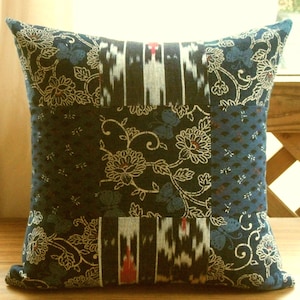 May include: A blue and white patchwork pillow cover with a floral pattern. The pillow cover is made of different fabrics with various patterns, including a floral design, a geometric pattern, and a striped pattern.
