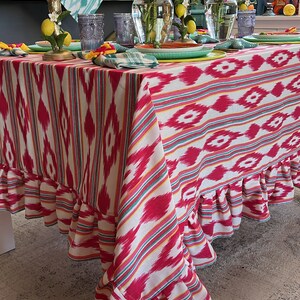 Peut inclure: Une nappe ray&eacute;e rose et blanche avec un bord festonn&eacute;. La nappe est dress&eacute;e pour un d&icirc;ner avec des fleurs, des bougies et des citrons.