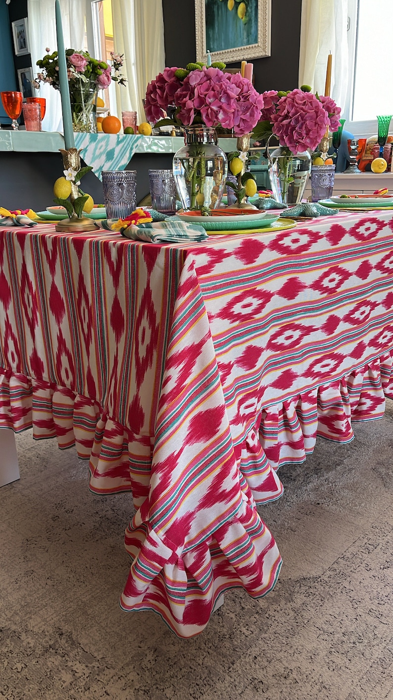 Peut inclure: Une nappe ray&eacute;e rose et blanche avec un bord festonn&eacute;. La nappe est dress&eacute;e pour un d&icirc;ner avec des fleurs, des bougies et des citrons.