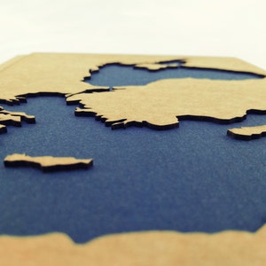 May include: A wooden map of the world with a blue background. The map is cut out to show the continents and oceans.
