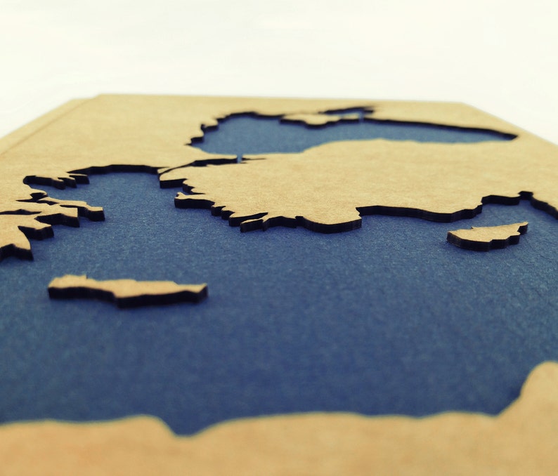 May include: A wooden map of the world with a blue background. The map is cut out to show the continents and oceans.