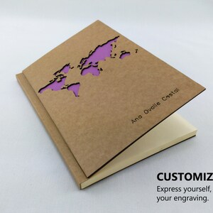 Puede incluir: Una libreta marr&oacute;n con un recorte en forma de mapa del mundo y una inscripci&oacute;n personalizada que dice "Ana Ovalle Costal".