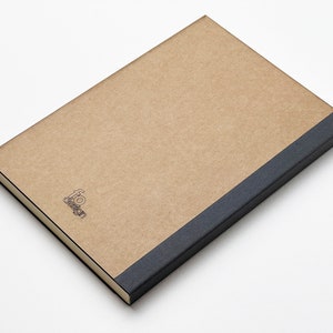 a brown notebook with a black cover on a white surface