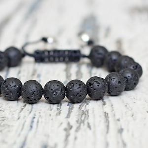 May include: A black lava rock beaded bracelet with a black cord and silver metal clasps.