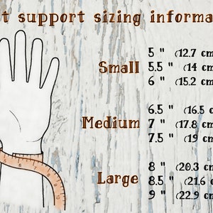 Op de afbeelding: Afbeelding met informatie over de maatvoering van polssteunen. Een hand is afgebeeld met een meetlint om de pols. Maten worden vermeld als Klein (12,7 cm tot 15,2 cm), Medium (16,5 cm tot 19 cm) en Groot (20,3 cm tot 22,9 cm).