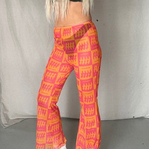 May include: Pink and orange mesh flared pants with a repeating pattern of a silhouette of a group of people and the text "Everybody Dance".