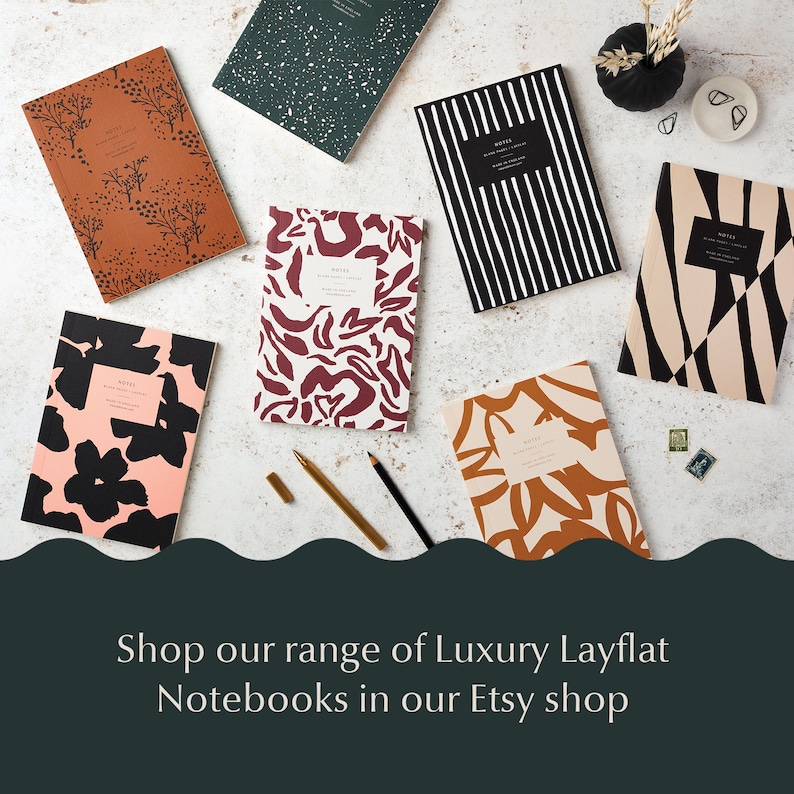 May include: Assortment of colorful notebooks with various abstract patterns, including floral, geometric, and animal print designs. The notebooks are arranged on a white surface with a gold pen and pencil. The text "NOTES" is visible on the front of each notebook.