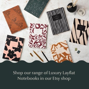 May include: Assortment of colorful notebooks with various abstract patterns, including floral, geometric, and animal print designs. The notebooks are arranged on a white surface with a gold pen and pencil. The text "NOTES" is visible on the front of each notebook.