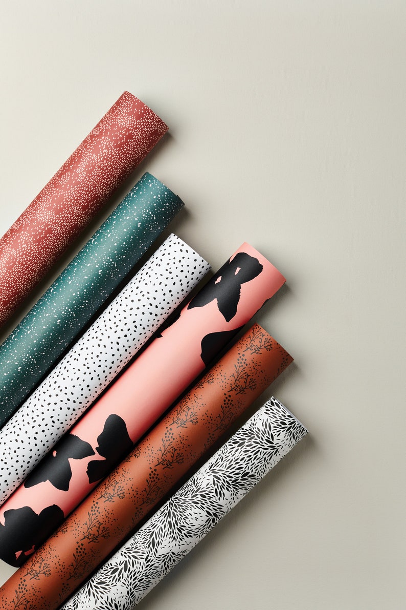 May include: Six rolls of wrapping paper with different patterns. The patterns include black and white polka dots, black and white floral designs, and black and pink floral designs.