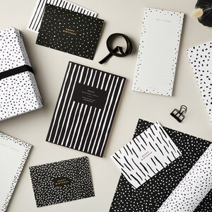 May include: Black and white patterned wrapping paper, notepads, and greeting cards. The designs include polka dots, stripes, and scribbles. The text on the cards reads "Happy Birthday".