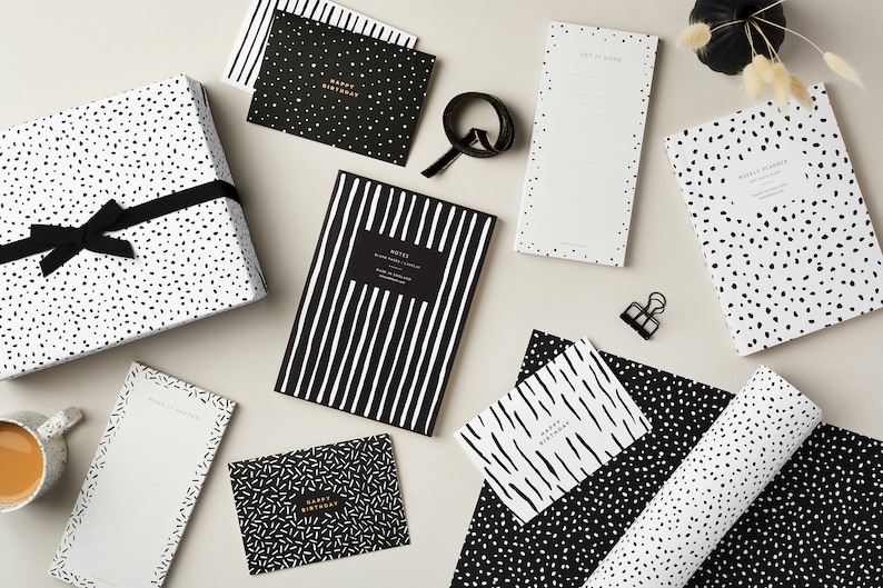 May include: Black and white patterned wrapping paper, notepads, and greeting cards. The designs include polka dots, stripes, and scribbles. The text on the cards reads "Happy Birthday".