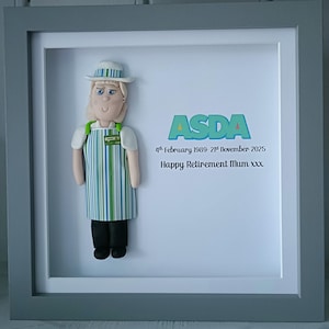 Può includere: Un'opera d'arte incorniciata con una statuina di una persona in uniforme ASDA, con cappello bianco e grembiule a righe verdi e blu. Sono inclusi anche il testo "ASDA" e un messaggio di pensionamento.