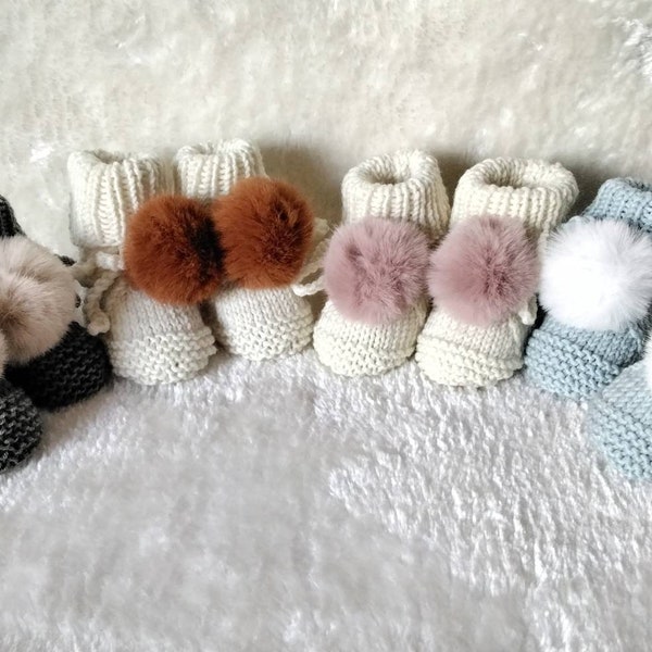 Hand-knitted baby slippers in 100% merino yarn and their faux fur pompoms, size 3.6 months