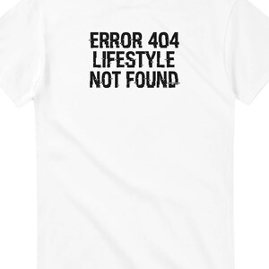 May include: White t-shirt featuring the text "ERROR 404 LIFESTYLE NOT FOUND" in a glitch-effect font. The tee has a classic crew neck design, ideal for everyday wear. The text is centrally positioned on the front.