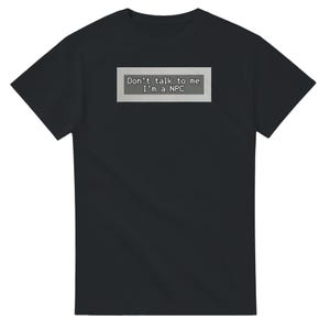 Könnte beinhalten: Schwarzes T-Shirt mit dem Text "Don't talk to me I'm a NPC" in weißer, pixeliger Schrift in einem grauen Rechteck. Das Shirt hat einen klassischen Rundhalsausschnitt.