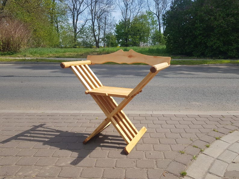 May include: A wooden folding chair with a curved back and a simple design. The chair is made of natural wood and has a light brown color.