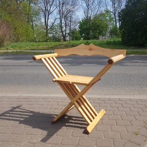 May include: A wooden folding chair with a slatted back and seat. The chair is made of natural wood and has a simple, rustic design.