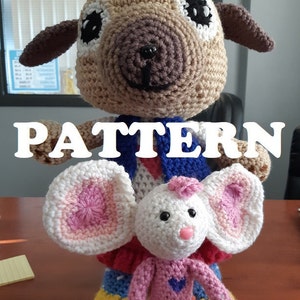 May include: A large, crocheted dog doll with brown and tan fur, wearing a blue vest and red and white patterned shirt. A smaller crocheted mouse doll with pink ears and a pink dress is in front. The word "PATTERN" is across the image.