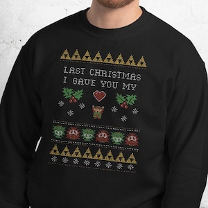 May include: Black sweatshirt with a festive design. The text "LAST CHRISTMAS I GAVE YOU MY" is displayed above a heart, reindeer, and holly. Below are pixelated characters. The design is in shades of green, red, and gold.