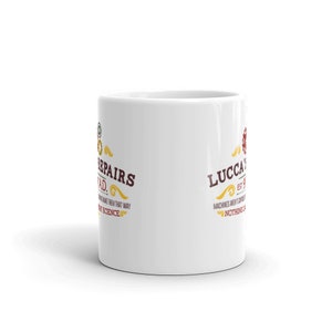 May include: White ceramic mug with the text "REPAIRS SQUAD" and "LUCCA'S" in a vintage style. The mug features a gear design and the phrase "Machines aren't born, nothing is".