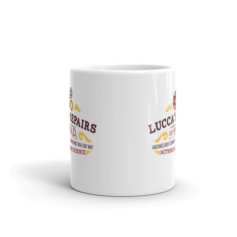 May include: White ceramic mug with the text "REPAIRS SQUAD" and "LUCCA'S" in a vintage style. The mug features a gear design and the phrase "Machines aren't born, nothing is".
