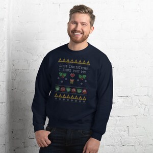 May include: Navy blue sweatshirt with a festive design. The design includes the text "LAST CHRISTMAS I GAVE YOU MY" above a heart, snowflakes, and other holiday-themed graphics. The sweatshirt is a comfortable, casual garment.