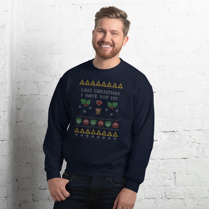 May include: Navy blue sweatshirt with a festive design. The design includes the text "LAST CHRISTMAS I GAVE YOU MY" above a heart, snowflakes, and other holiday-themed graphics. The sweatshirt is a comfortable, casual garment.
