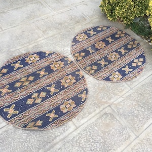 May include: Two round blue and cream patterned rugs with geometric designs. The rugs are on a light gray tiled floor.