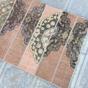 May include: A vintage rug with a patchwork design featuring various shades of brown, pink, and beige. The rug has a geometric pattern with intricate details.