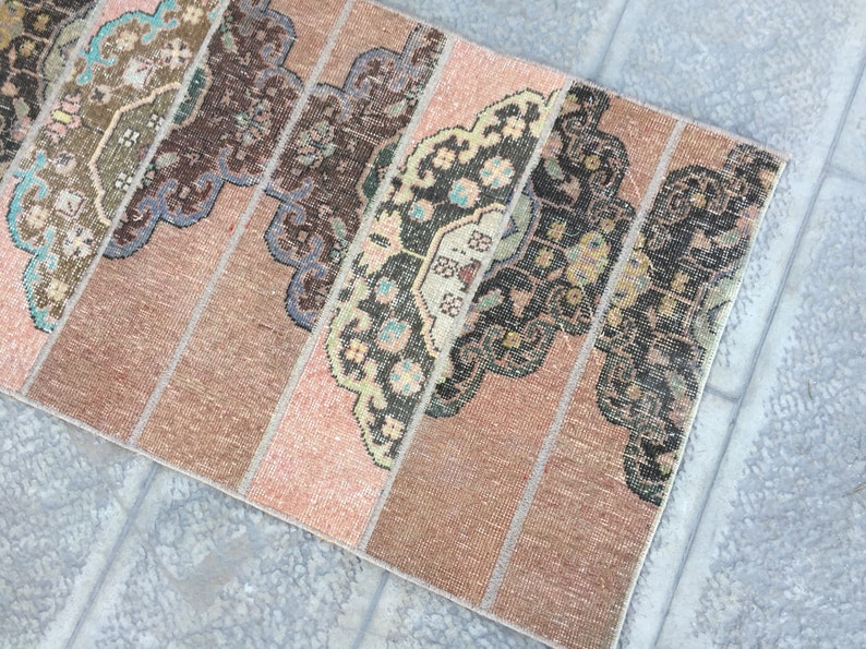 May include: A vintage rug with a patchwork design featuring various shades of brown, pink, and beige. The rug has a geometric pattern with intricate details.