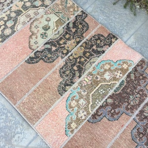 May include: A vintage pink and brown rug with a geometric pattern. The rug has a faded look and is made of woven fabric.