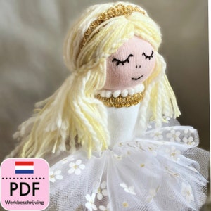 Peut inclure: Une poupée faite à la main avec des cheveux en laine blonde, une robe blanche et une couronne dorée. La poupée porte une jupe en tulle blanche avec des fleurs blanches.