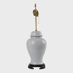 May include: A light gray ceramic ginger jar lamp with a brass neck and a black base. The lamp has a classic shape with a lid and a crackle glaze finish. The lamp is a decorative lighting fixture.