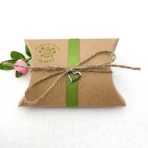K&ouml;nnte beinhalten: Eine braune Geschenkbox aus Papier mit einem gr&uuml;nen Band und einem silbernen Herzanh&auml;nger. Die Box ist mit Schnur gebunden und hat einen Stempel mit der Aufschrift "Handmade for you by PFYT".
