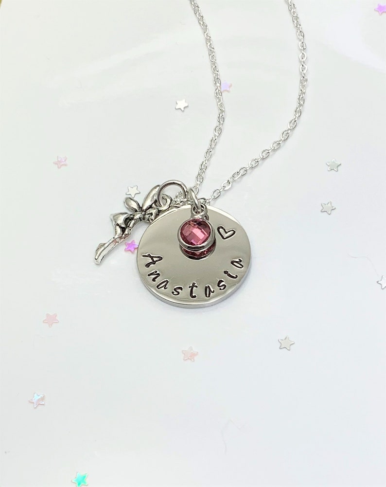 K&ouml;nnte beinhalten: Eine silberne Halskette mit einem Anh&auml;nger, auf dem "Anastasia" steht und der einen rosa Kristall und ein kleines Herz aufweist. Der Anh&auml;nger ist an einer silbernen Kette befestigt.
