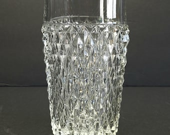 May include: A clear, vintage-style drinking glass with a diamond-cut pattern on the lower portion. The glass has a cylindrical shape with a smooth, rounded rim. The textured design adds visual interest to this glassware.