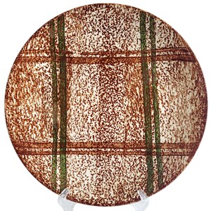 Pode incluir: Prato redondo de cerâmica com uma superfície texturizada salpicada de castanho e branco. O prato apresenta um design xadrez com linhas verticais e horizontais castanhas e verdes. O prato é exibido em um suporte transparente.