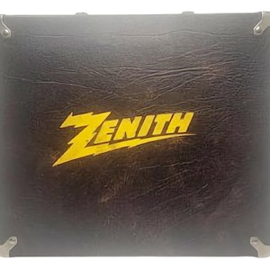 May include: A black amplifier case featuring the word "ZENITH" in yellow, stylized lettering. The case has metal corner protectors and a textured surface. The design is simple and functional, suggesting a focus on durability and performance.