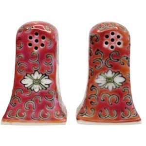 May include: A pair of ceramic salt and pepper shakers. The shakers are red with a floral design and green accents. Each shaker has a white flower with green leaves and a series of holes at the top for dispensing.