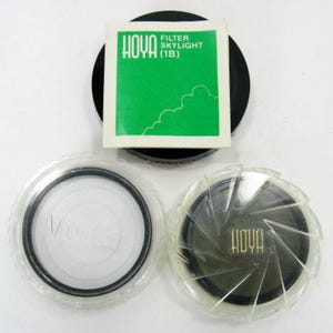 May include: Three round camera lens filters, two in clear plastic cases and one in a green and white box. The box has the text "HOYA FILTER SKYLIGHT (1B)".