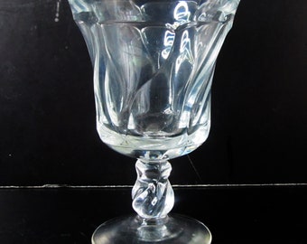 May include: A clear glass goblet with a twisted stem and a fluted bowl.