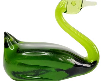 May include: A green glass swan figurine with a light green head and neck. The swan is in a graceful pose with its head turned to the side.