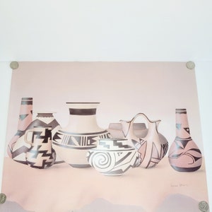 May include: A collection of six Native American pottery vessels in various shapes and sizes. The pottery is decorated with black and white geometric patterns on a light brown background. The vessels are arranged on a light brown surface. The signature "Louis Starr" is visible in the bottom right corner.