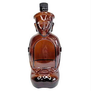 May include: A brown glass bottle shaped like a figure with a black cap. The bottle has a detailed face and body design. The bottle is empty and ready to be filled.