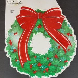 May include: A red and white paper Christmas wreath with a large red bow. The wreath is printed on both sides.
