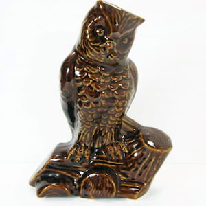 May include: A brown ceramic owl figurine perched on a tree stump. The owl has detailed feathers and realistic eyes.