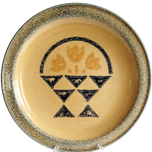 以下が含まれることがあります： 緑色の斑点のある縁取りと黄色の背景を持つセラミック製のサービングディッシュ。中央には、バスケットに入った3つのスタイリッシュなチューリップの黒と黄色のデザインが施されています。