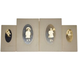 Puede incluir: Cuatro marcos de fotos ovalados vintage con fotos en blanco y negro de niños. Los marcos son de color beige y tienen un borde elevado alrededor de las fotos.