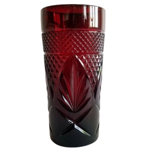 Puede incluir: Un vaso alto y transparente con un tono rojo intenso y un patrón de diamante. El vaso tiene un diseño único con un patrón de hoja en el centro.