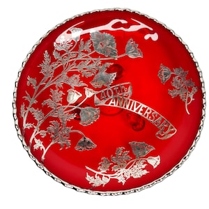 Puede incluir: Un plato de servir de vidrio rojo con un borde plateado y un diseño floral. El plato tiene una inscripción plateada que dice "40 aniversario".